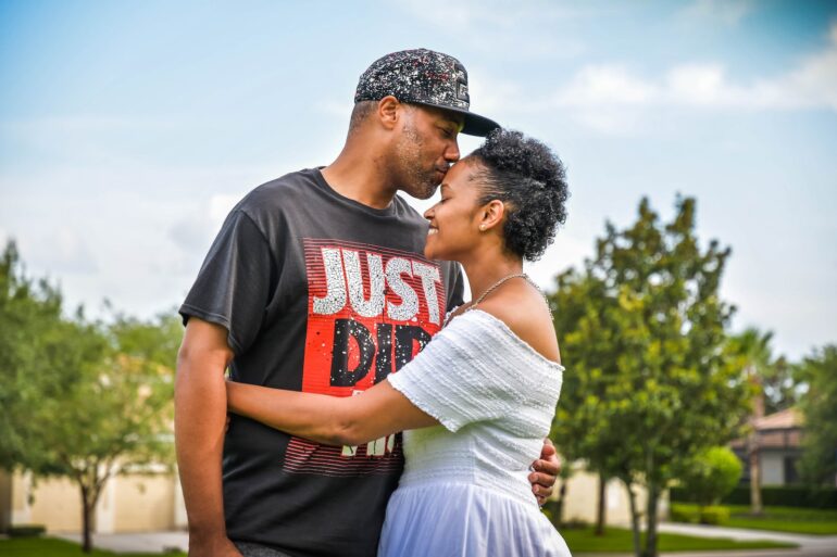 man in black crew neck t-shirt kissing woman in white dress