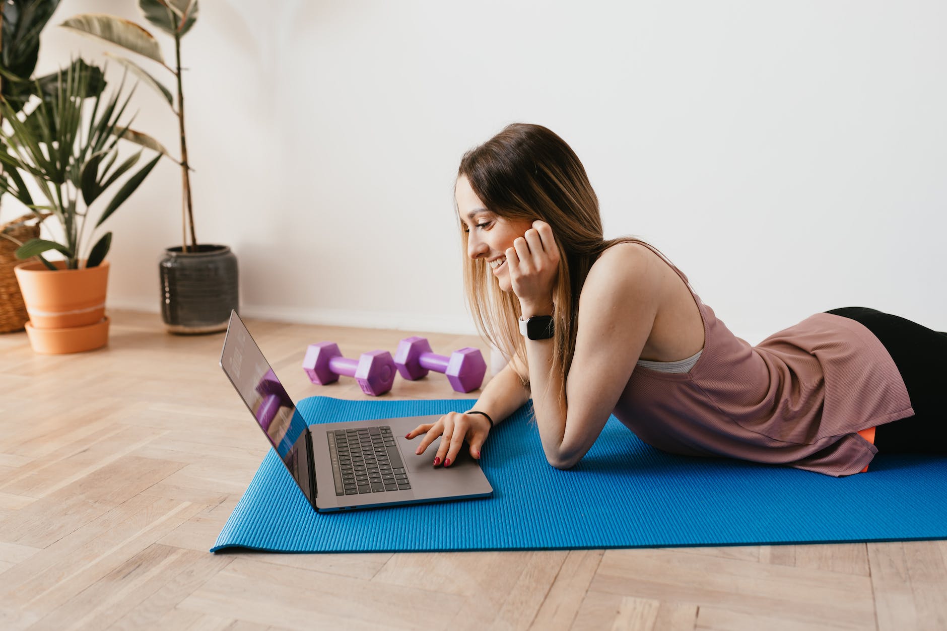 slim woman browsing laptop on yoga mat